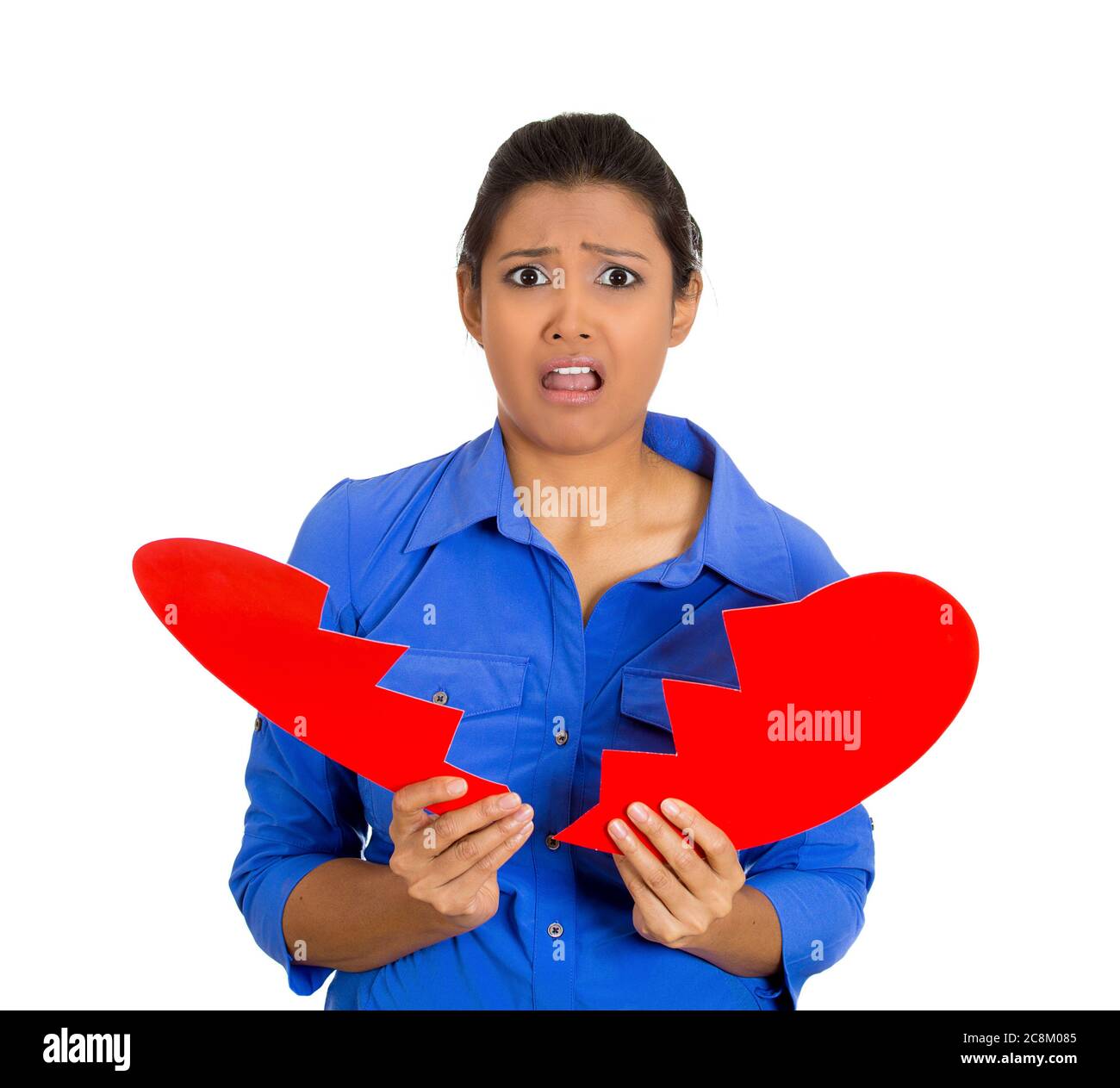 Portrait of a young sad, depressed, confused woman, holding broken heart in her hands isolated on white background. Stock Photo