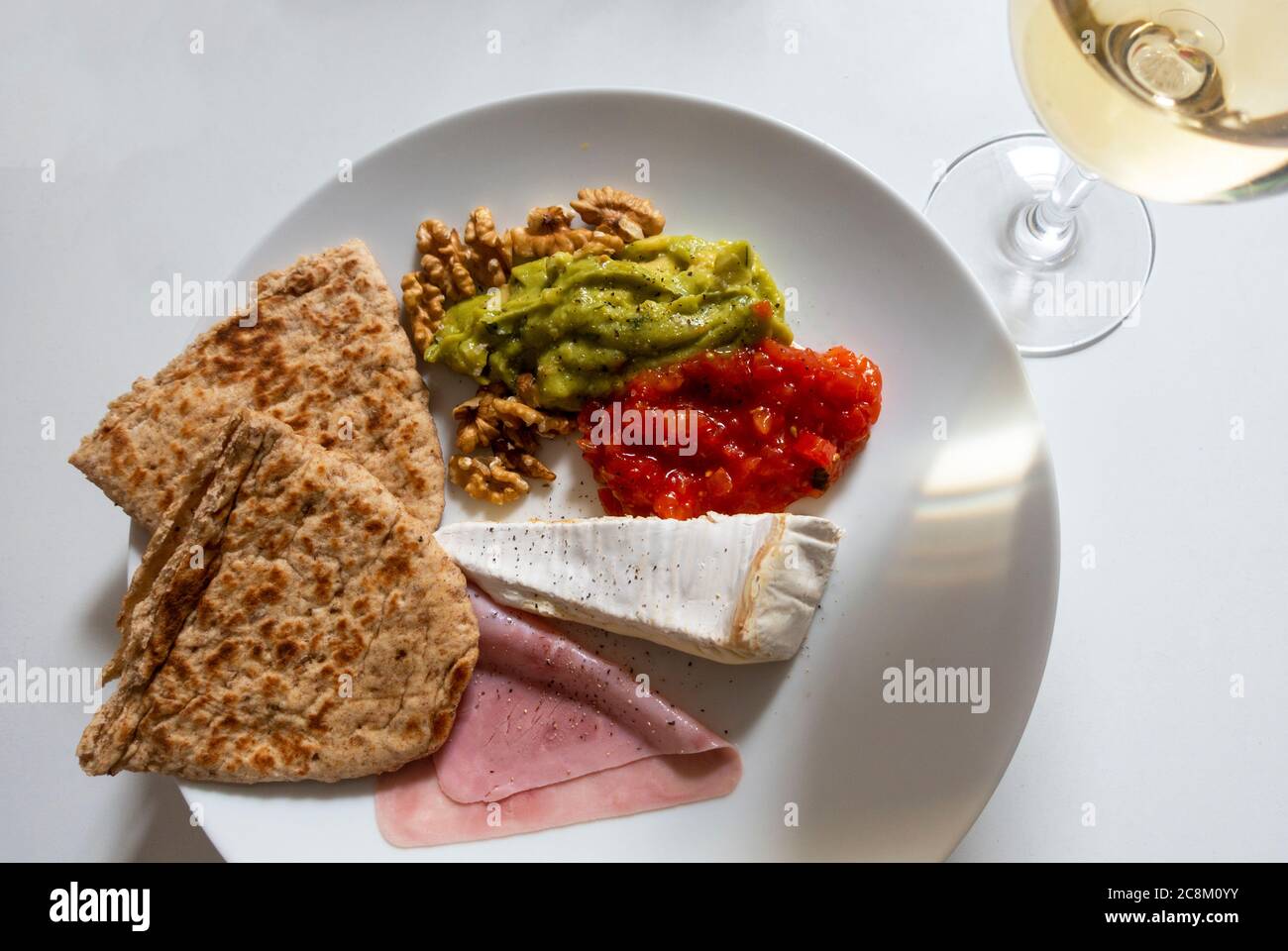 A mixed platter of cold antipasto with a glass of white wine Stock Photo