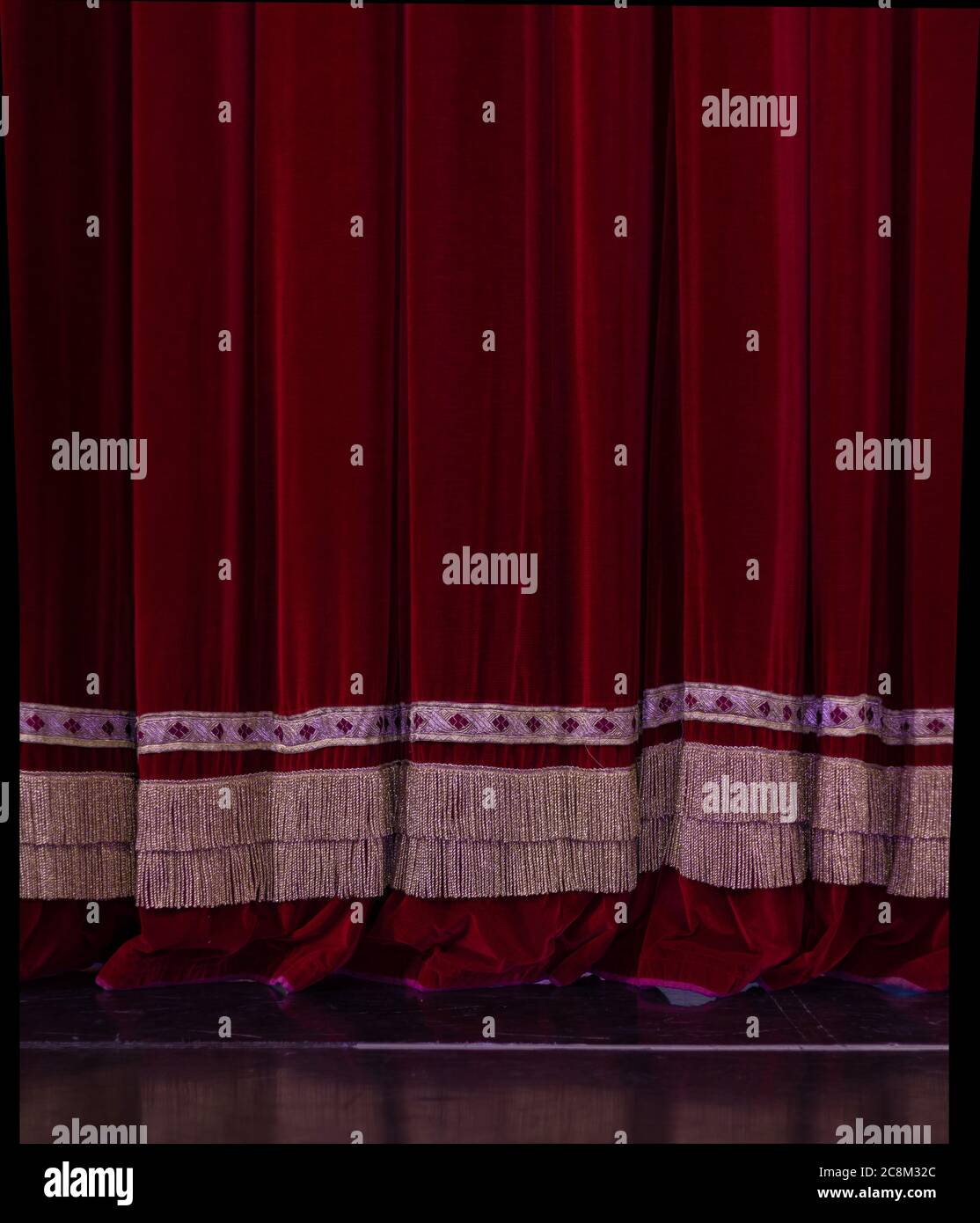 Theatrical dark red velvet curtain with golden fringe. Texture ...