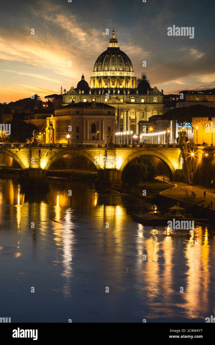 The lights around the Vatican and St. Peters Basilica reflect in the Tiber River in Rome, Italy. Stock Photo