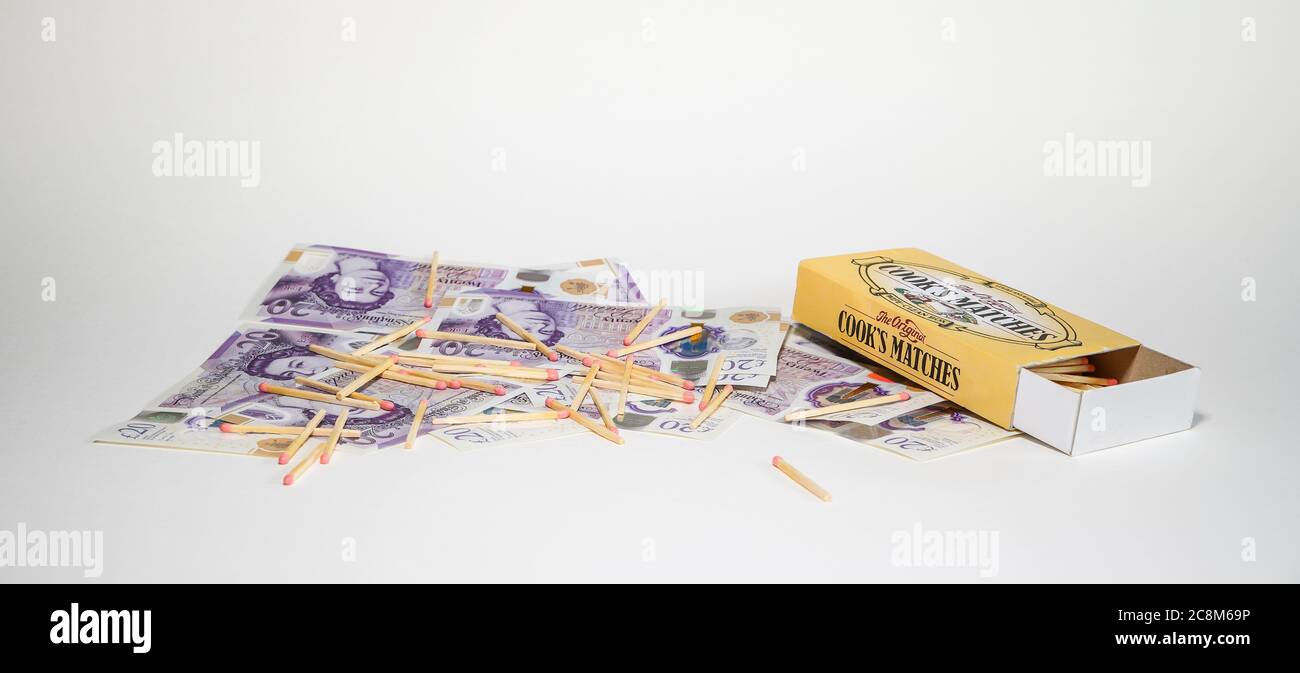 Twenty pound notes on white background covered in unstruck matches & open matchbox. Concept having money to burn, more than enough, extravagance. Stock Photo