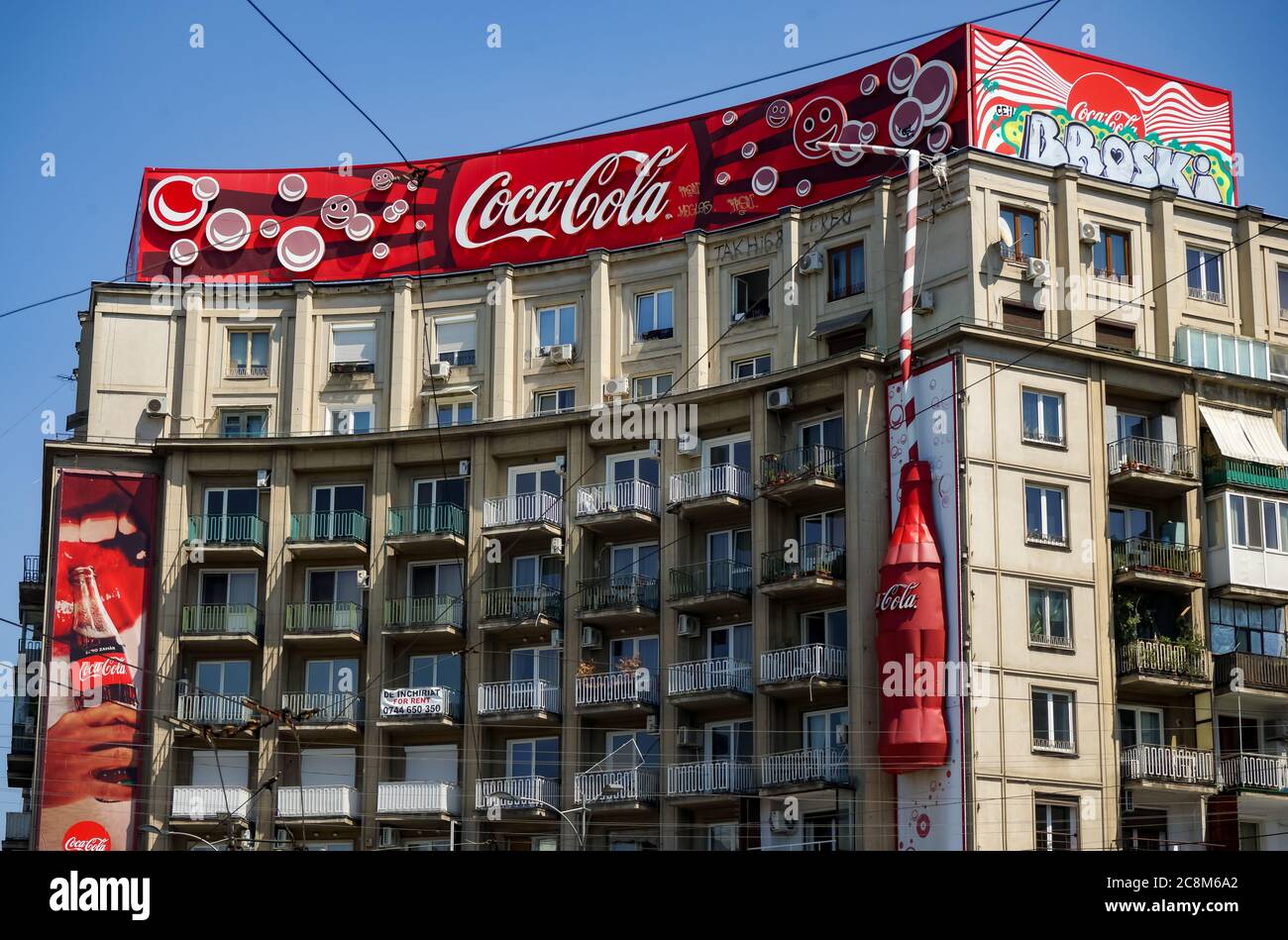 Bucharest, Romania -  June 28, 2020: A very large logo of Coca-Cola soft drink manufacturer is displayed on the top of a block of flats, in Piata Roma Stock Photo