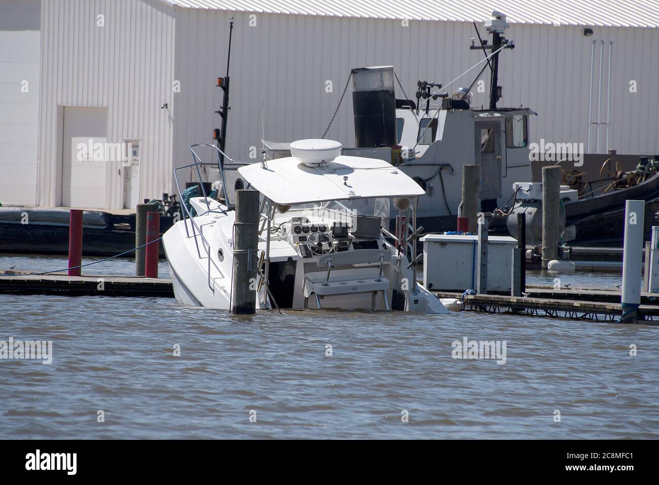 white power boat sinking in marina slip Stock Photo