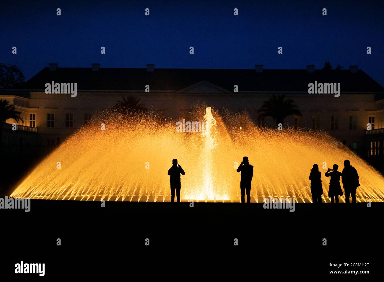 Hanover, Germany. 25th July, 2020. Visitors view the illumination in the Herrenhäuser Gardens. During the summer months until autumn, after dusk, the magnificent fountains, bubbling fountains and imposing figures in the Great Garden shine out after dark. Herrenhausen in festive lighting, accompanied by baroque music. Credit: Peter Steffen/dpa/Alamy Live News Stock Photo