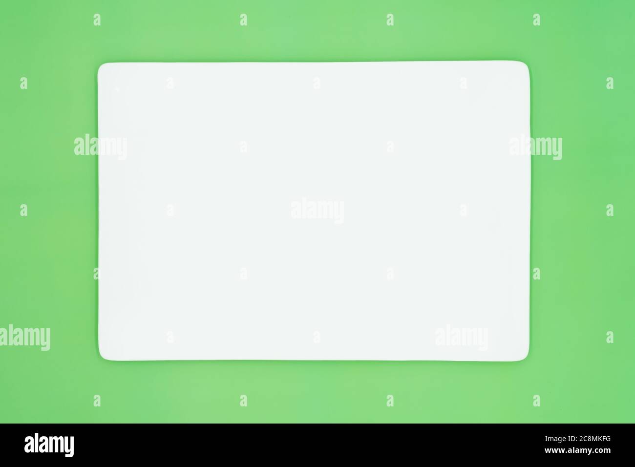 A rectangle empty white plate isolated on the light green background. Stock Photo