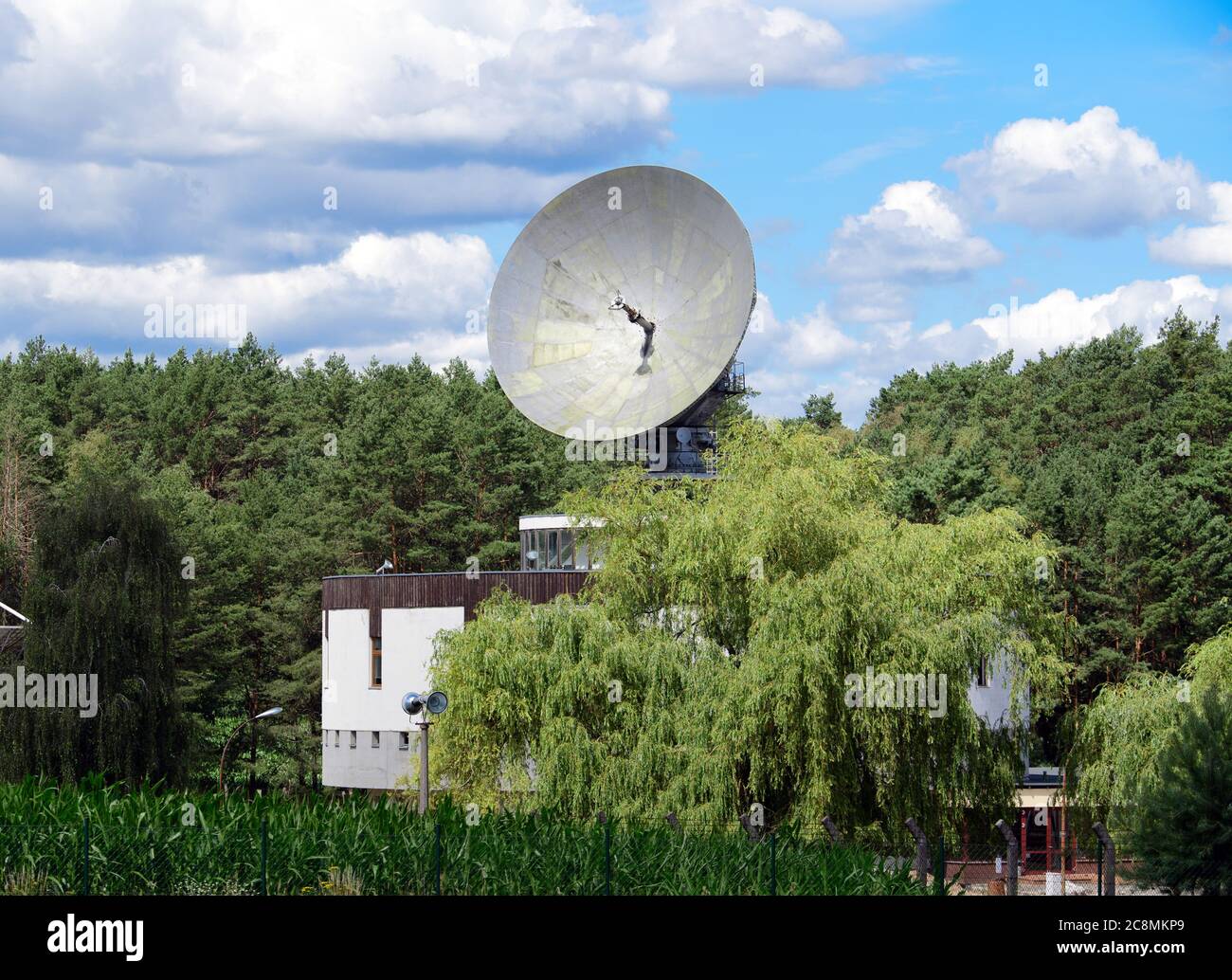 22 July 2020, Brandenburg, Bad Saarow/Ot Neu-Golm: The 12-meter parabolic  antenna of the former Intersputnik satellite ground station can be seen  above the trees on the cylindrical building of the Orbita-2 type.