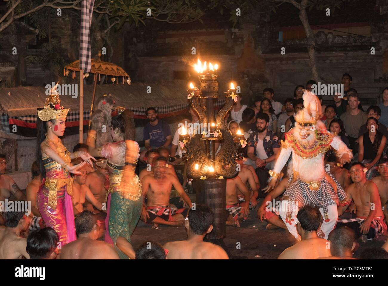 Dramatic photo of colorfully dressed Kecak dancers dressed in traditional, brightly colored costumes perform Balinese Hindu Ramayana Temple dance. Stock Photo