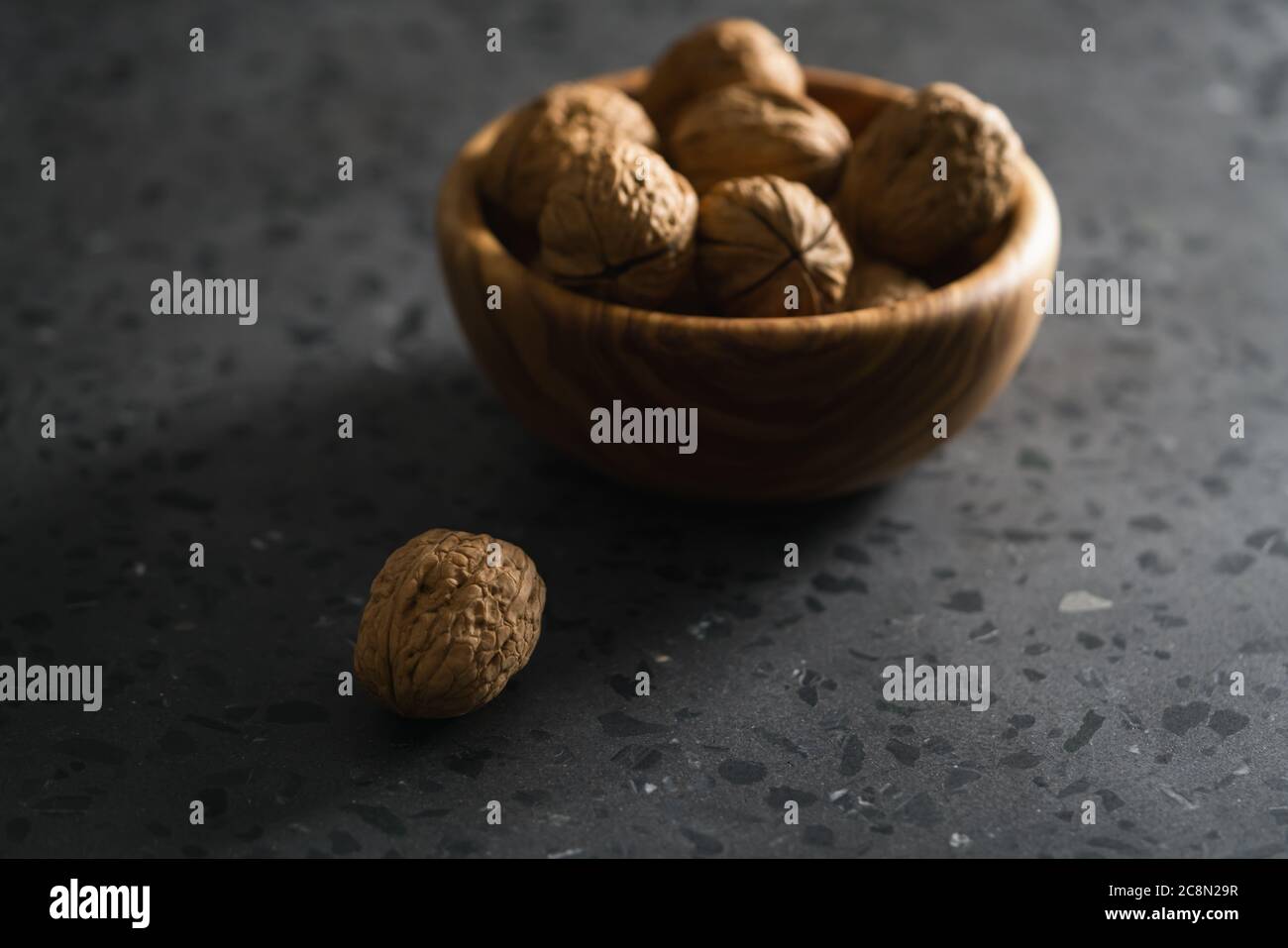 inshell walnuts in olive wood bowl on terrazzo countertop Stock Photo