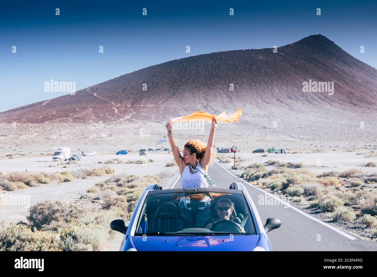 Happiness and travel lifestyle concept with beautiful woman outside a convertible blue car enjoy the freedom and have fun on the road with her female Stock Photo