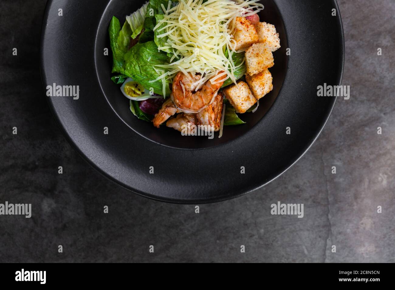 Italian cuisine. Salad with fresh salad greens, shrimp and quail eggs. Dark key photo Stock Photo