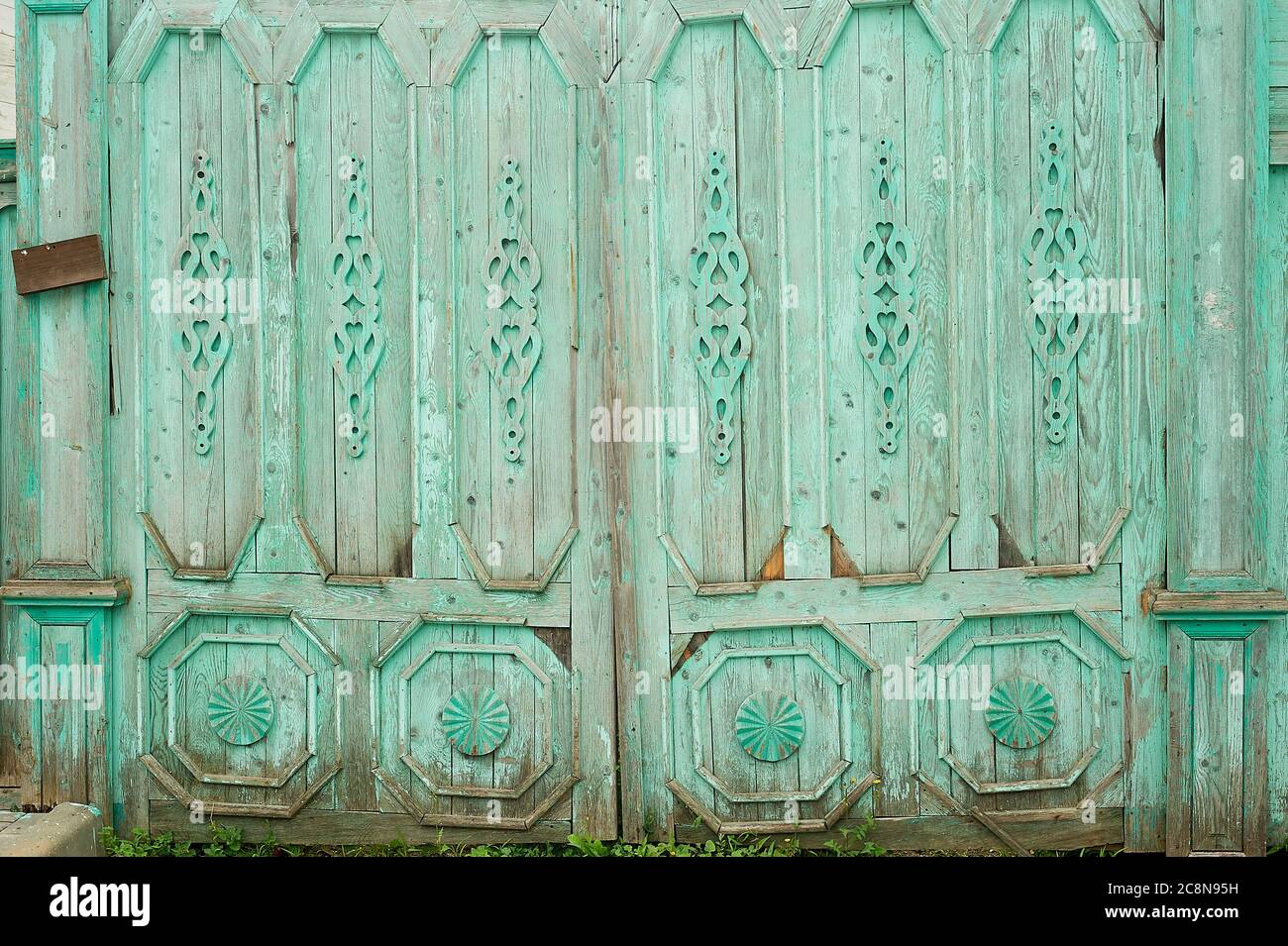 Wooden wide gates in old Russian houses. Figurative ornaments made of wood.Bright colors. Ancient wooden Russian houses. Stock Photo