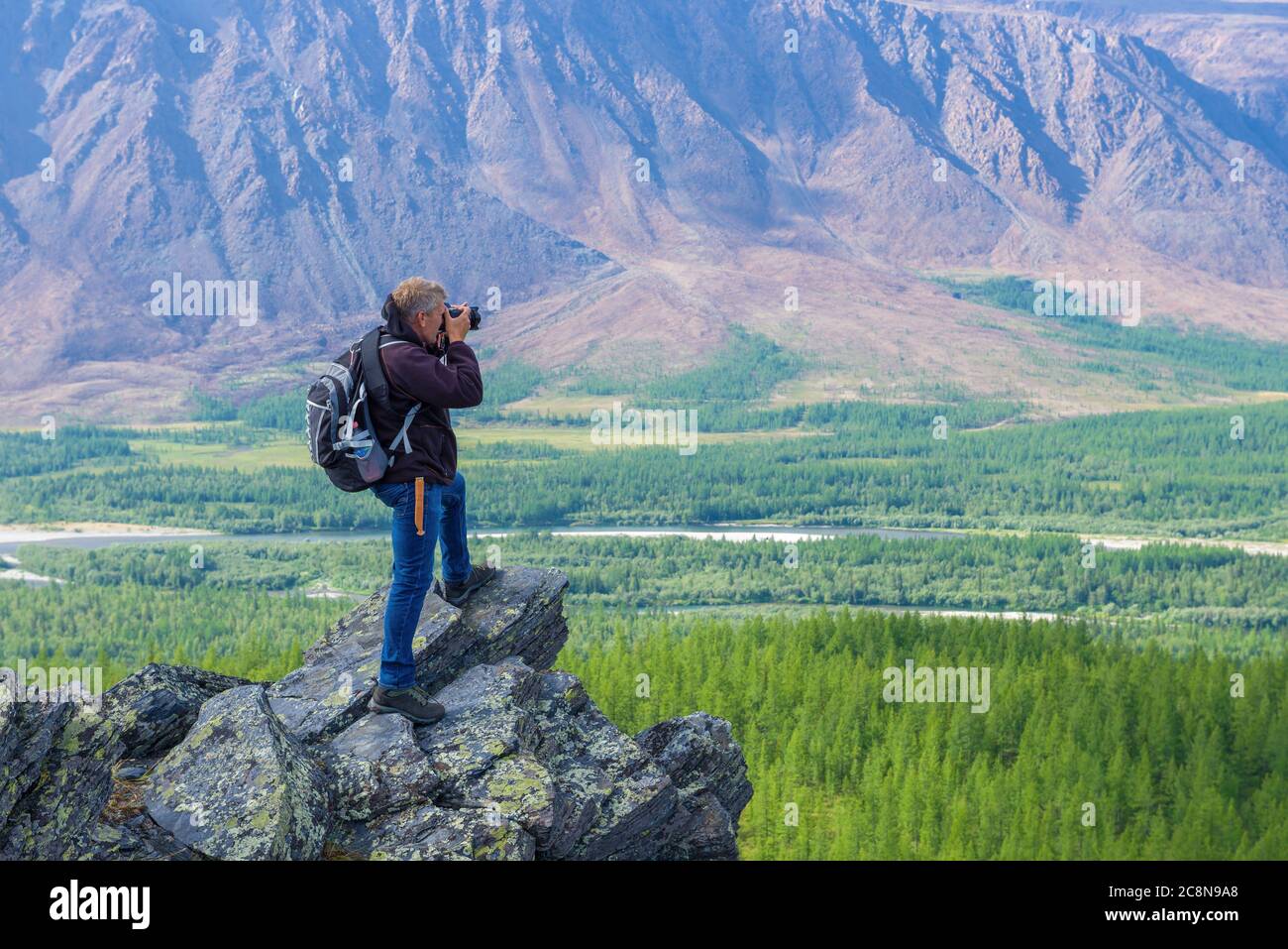 TYUMEN REGION, RUSSIA - AUGUST 20, 2019: Travel photographer on the set in the mountains of the Polar Urals. Stock Photo