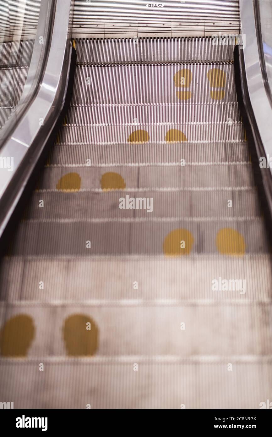 Foot point print sign on escalator in yellow to maintain distance during the Covid-19 pandemic, health care, Stock Photo