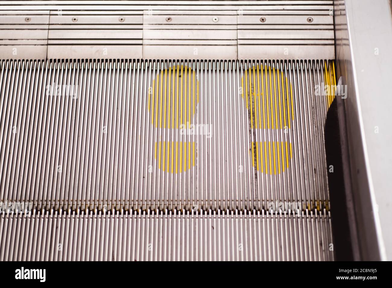 Foot point print sign on escalator in yellow to maintain distance during the Covid-19 pandemic, health care, Stock Photo