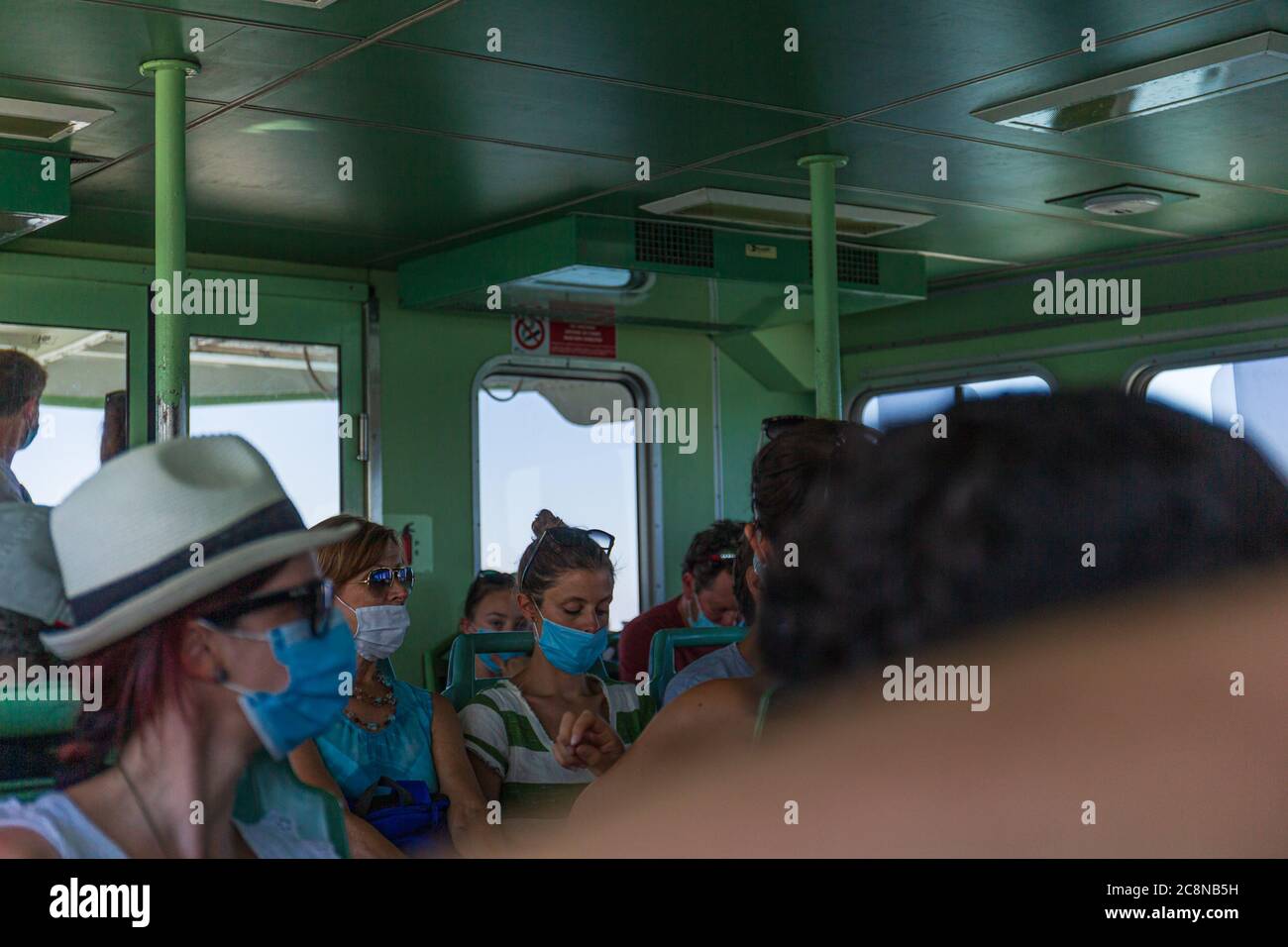 Venice, Italy - July 5th, 2020: People on board of a vaporetto wearing protective masks. Stock Photo