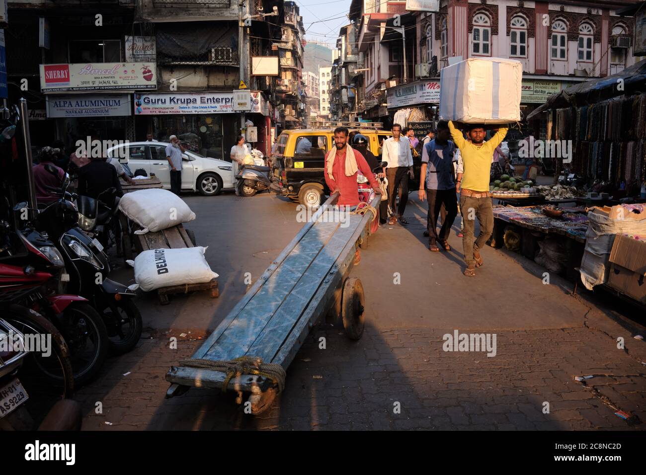 A man steers a handcart through busy Kalbadevi Rd. in Bhuleshwar, Mumbai, India, handcarts being the most used mode for goods transport in the area Stock Photo