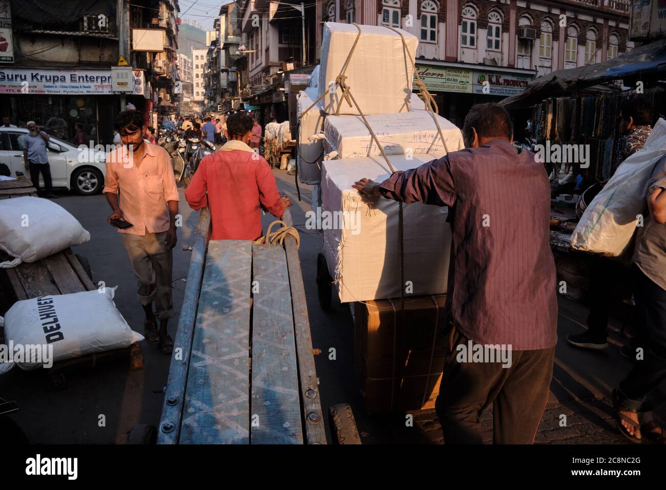 Men pull or pus handcarts through busy Kalbadevi Rd. in Bhuleshwar, Mumbai, India, handcarts being the most used mode for goods transport in the area Stock Photo