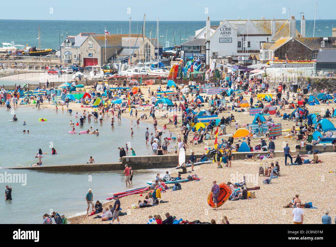 Lyme Regis, Dorset, UK. 26th July, 2020. UK Weather: Holidaymakers flock to the beach at Lyme Regis on a day of hot sunny spells and rain showers. Credit: Celia McMahon/Alamy Live News Stock Photo