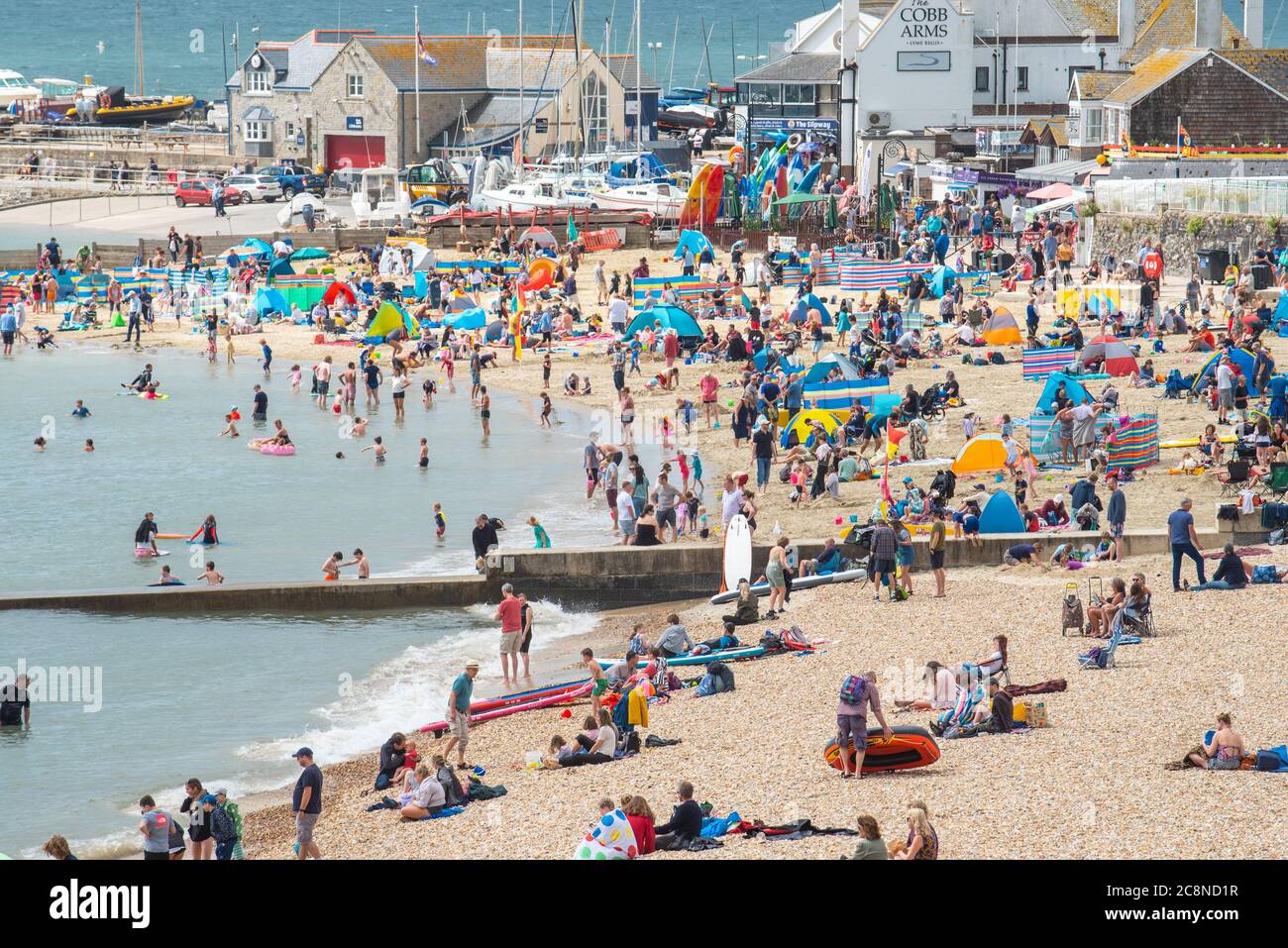 Lyme Regis, Dorset, UK. 26th July, 2020. UK Weather: Holidaymakers flock to the beach at Lyme Regis on a day of hot sunny spells and rain showers. Credit: Celia McMahon/Alamy Live News Stock Photo