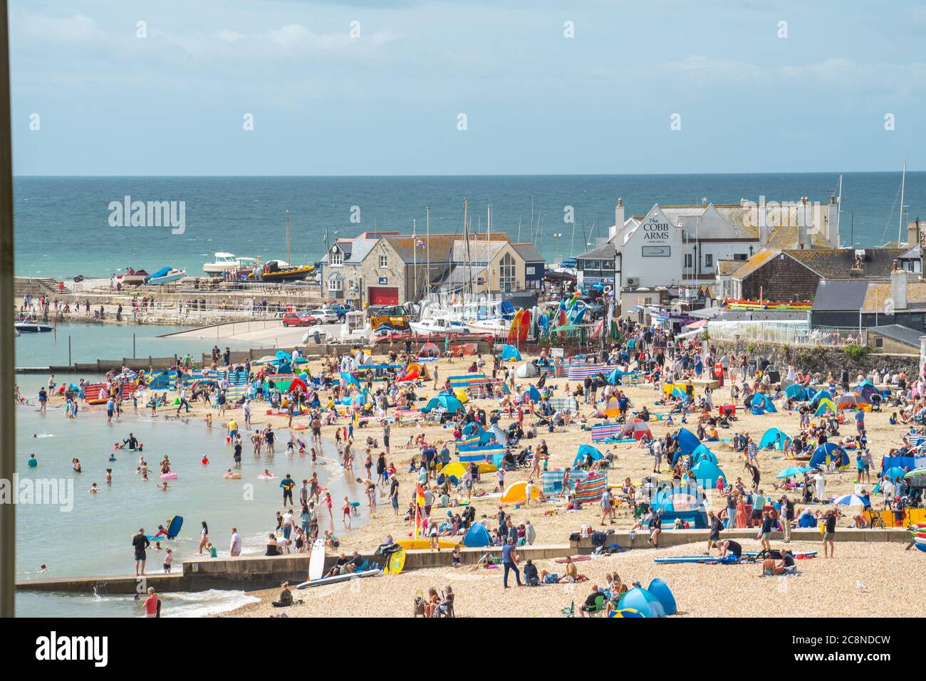 Lyme Regis, Dorset, UK. 26th July, 2020. UK Weather: Holidaymakers flock to the beach at Lyme Regis on a day of hot sunny spells and rain showers. Credit: Celia McMahon/Alamy Live News Stock Photo