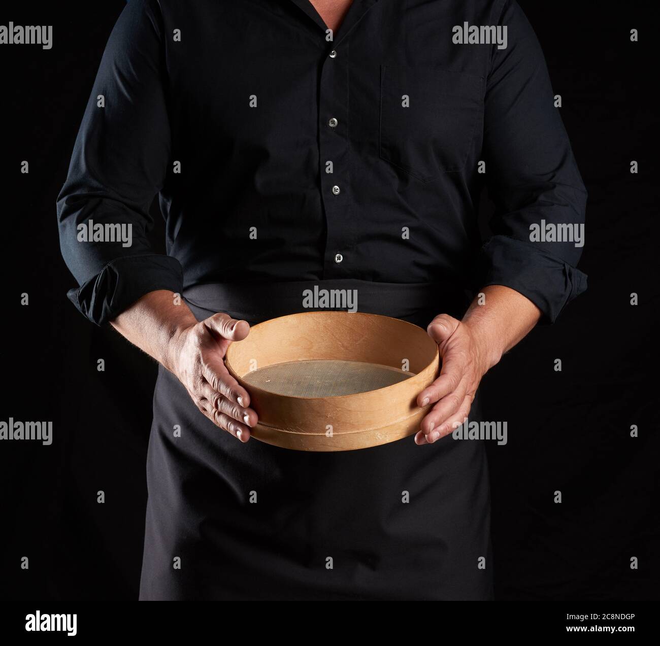 man in black uniform holding empty vintage round wooden sieve for ...