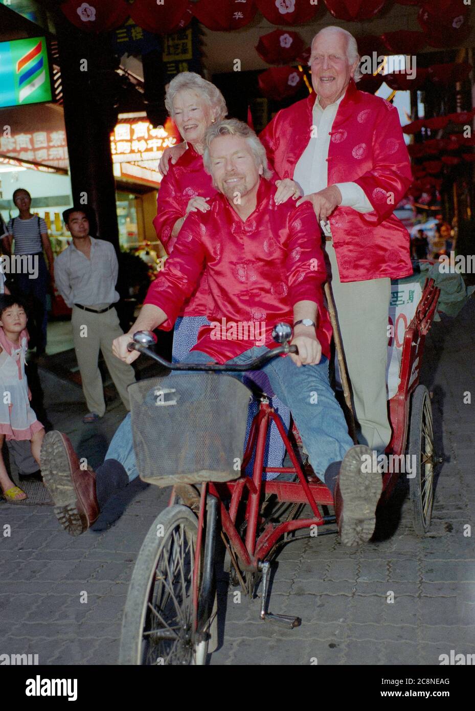 Sir Richard Branson founder of the Virgin group including Virgin Atlantic airlines with his parents Ted and Eve cycle through the streets of  Shanghai  celebrating the inaugural flight of the airlines operation from Heathrow to the Chinese city in July 1999. Stock Photo