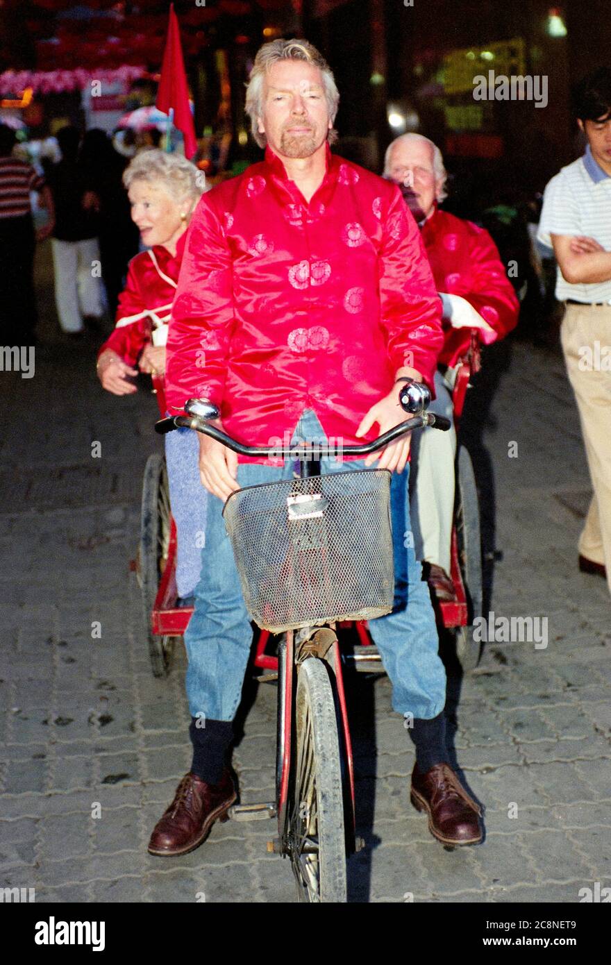 Sir Richard Branson founder of the Virgin group including Virgin Atlantic airlines with his parents Ted and eve cycle through the streets of  Shanghai  celebrating the inaugural flight of the airlines operation from Heathrow to the Chinese city in July 1999. Stock Photo