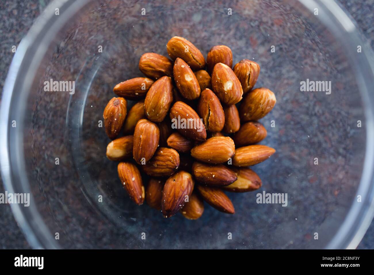 simple food ingredients concept, salted roasted almonds in clear bowl Stock Photo