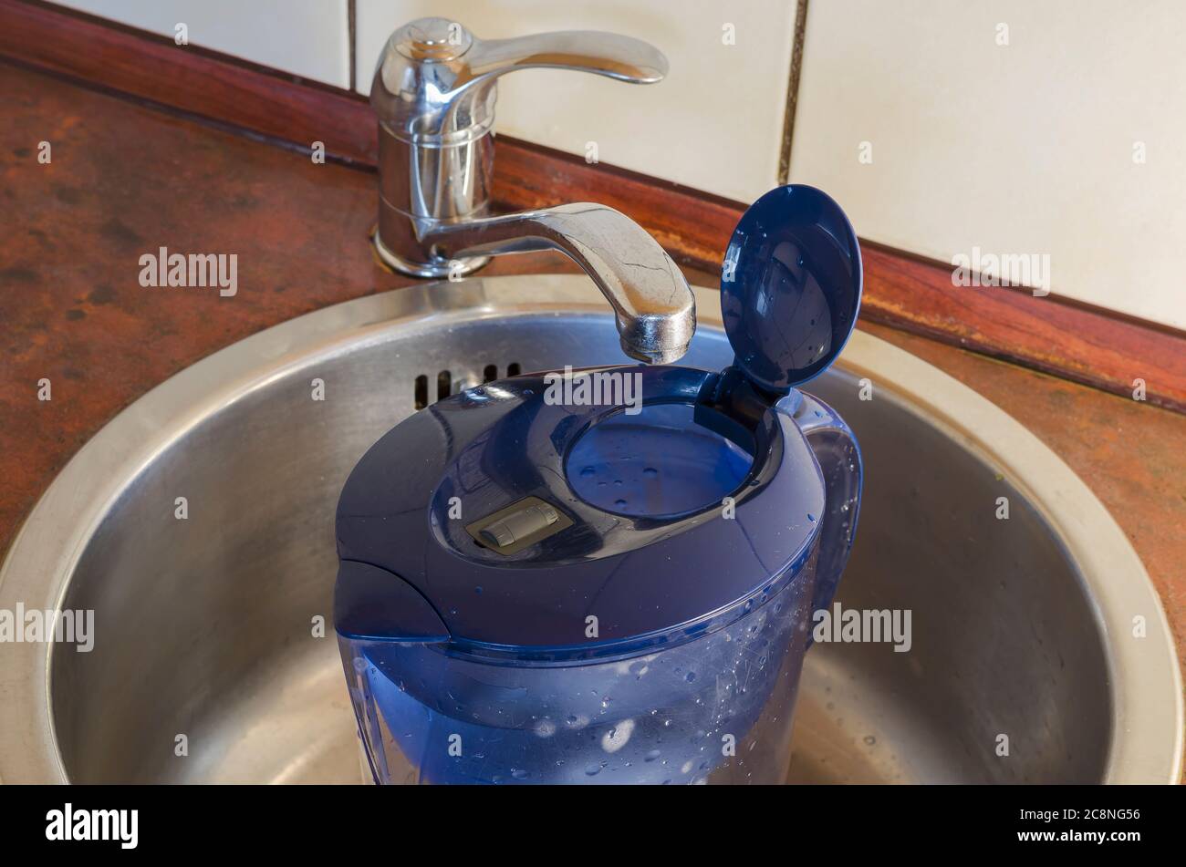 Water filter jug in the kitchen sink. Plastic jug filled with running