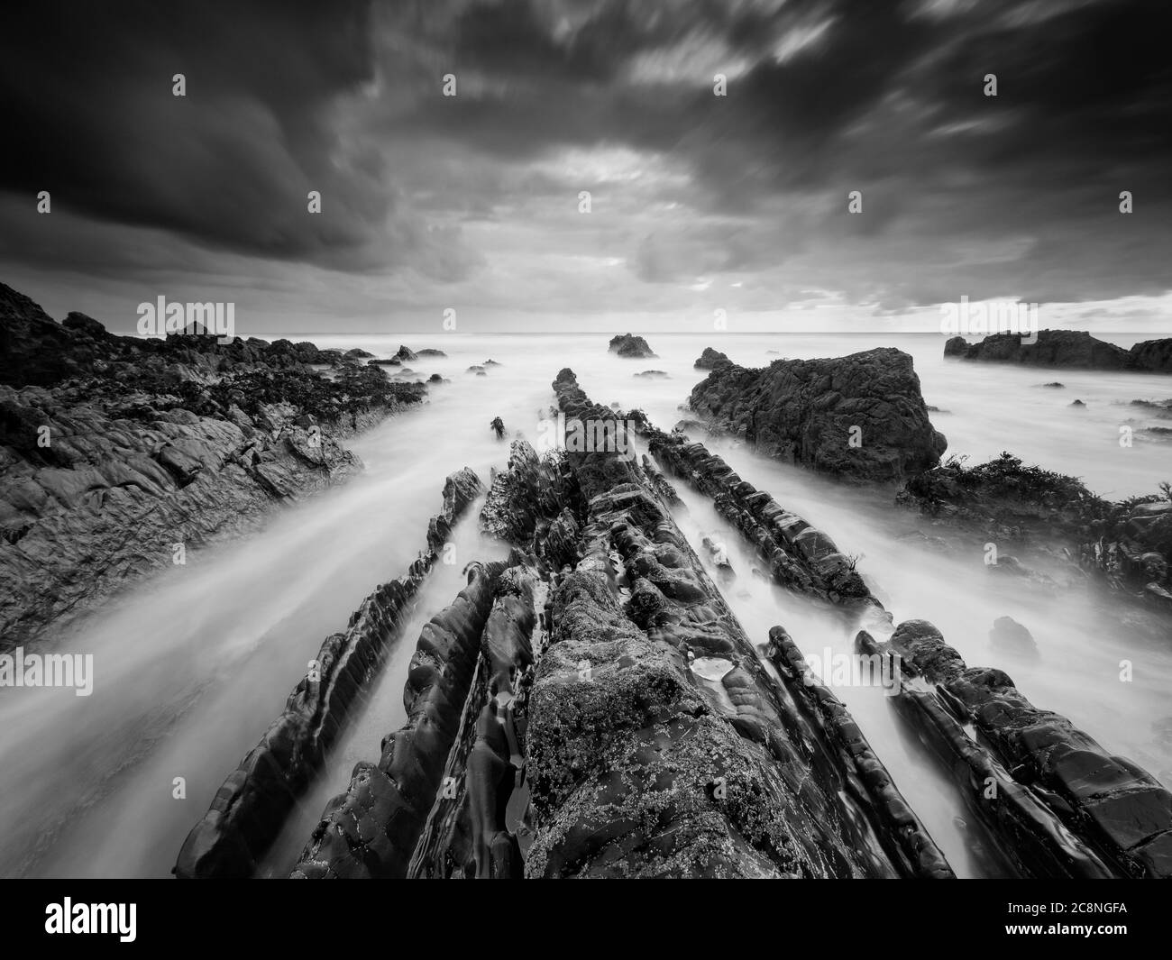 Lines of jagged rocks on Bude beach. Stock Photo