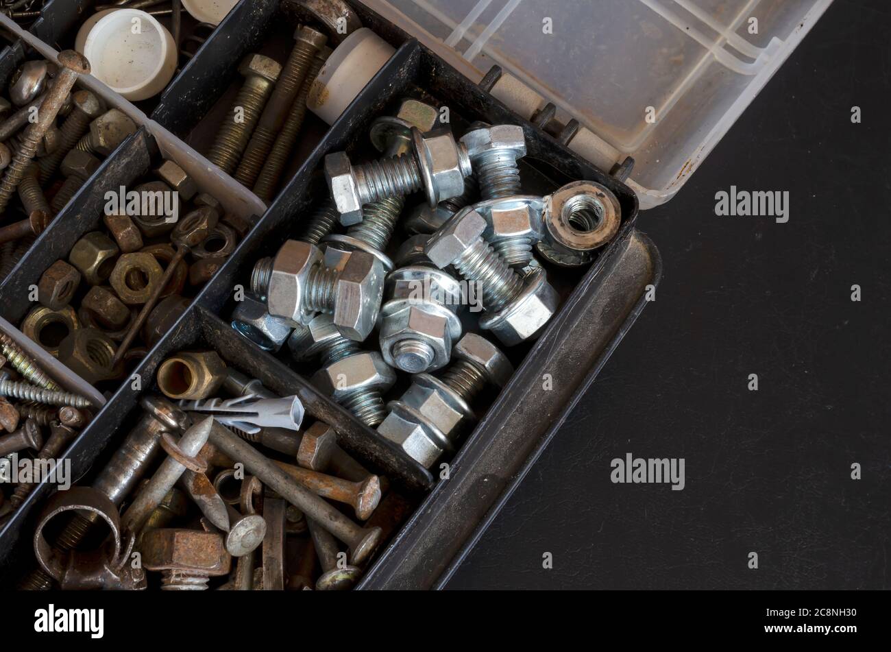 Plastic box with a variety of metal fasteners. Old and new bolts, nuts ...