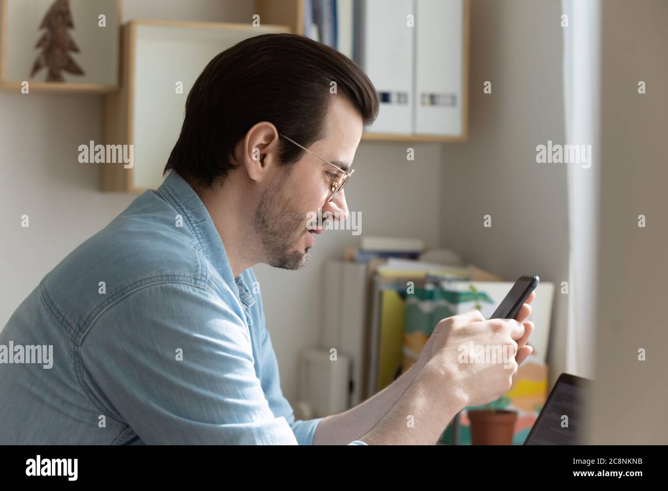 Focused Caucasian man texting on modern cellphone Stock Photo