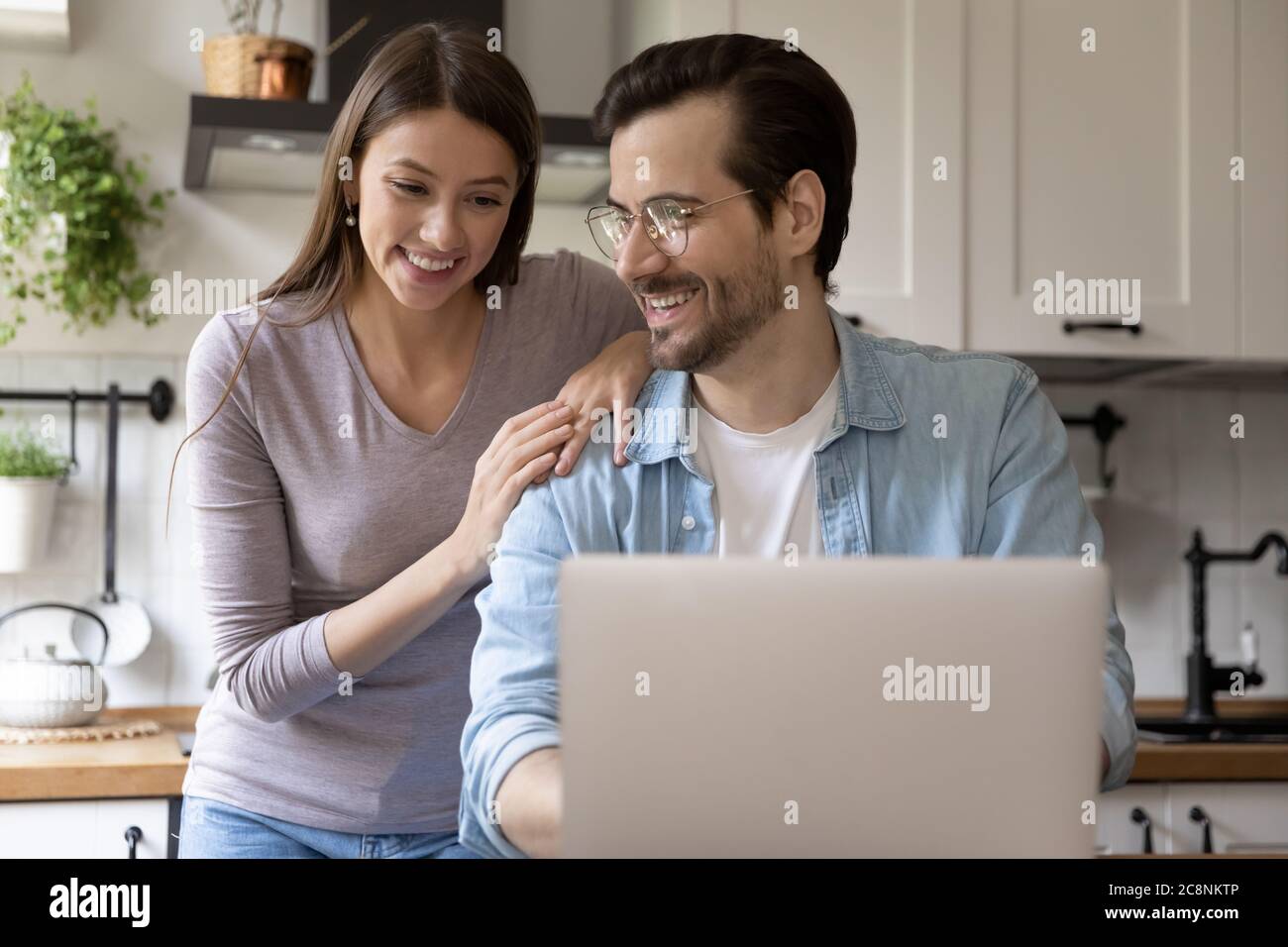 Smiling young couple have fun using laptop Stock Photo