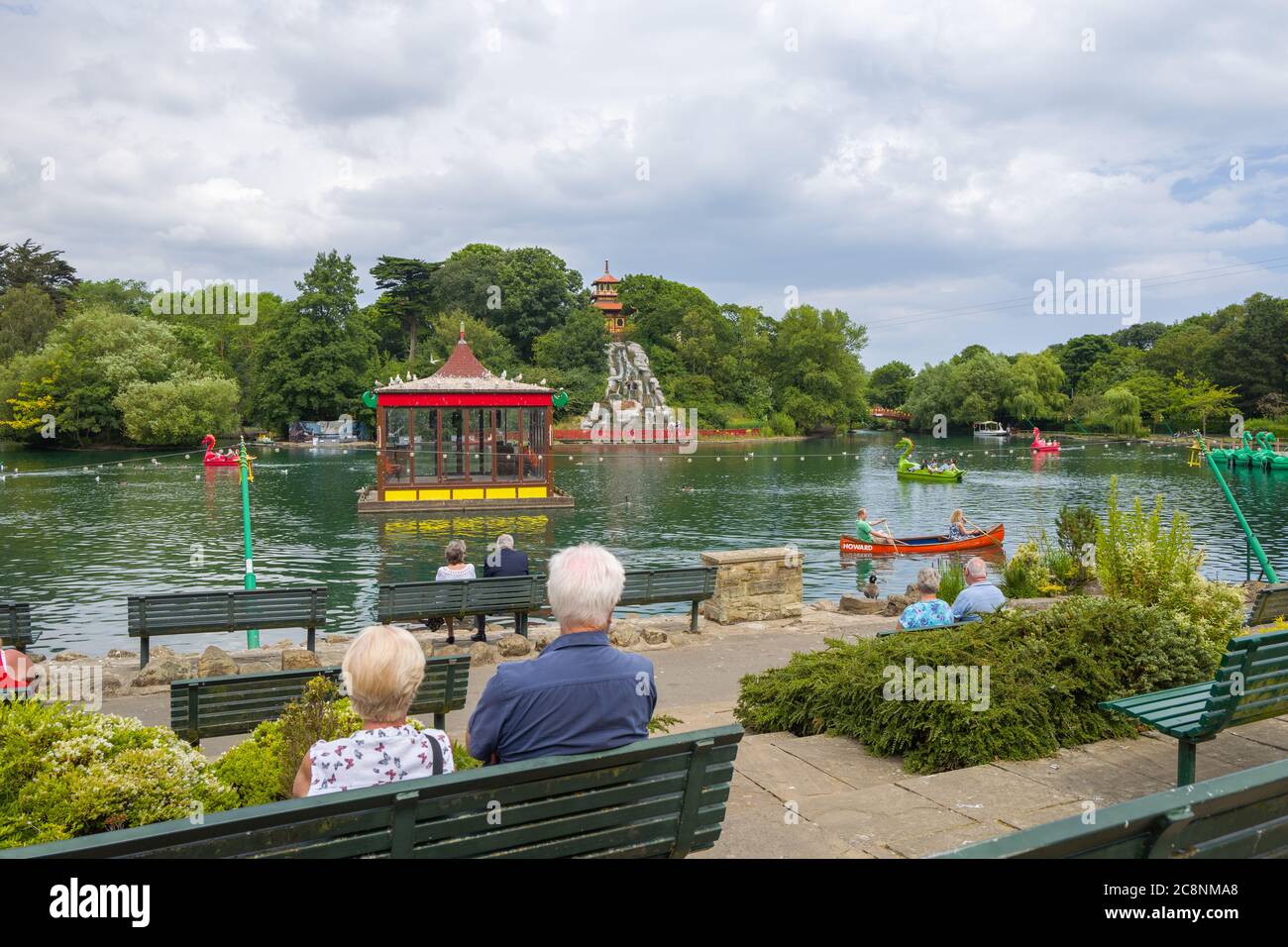 Visitors relaxing and enjoying the view at the Grade II listed Peasholm Park boating lake with its pagoda. Scarborough, North Yorkshire, UK. Stock Photo