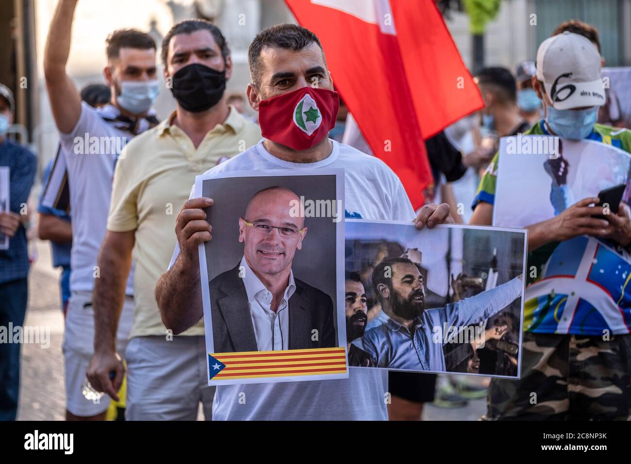 Barcelona, Spain. 25th July, 2020. A supporter of the Popular Rif Movement (Hirak) wearing a mask is seen showing placards with the former Minister of the Generalitat of Catalonia Raül Romeva and the leader and activist of Rif Nasser Zefzafi during the rally.Sympathizers of the Popular Rif Movement (Hirak) residing in Catalonia gathered in the Plaza Sant Jaume in Barcelona to commemorate the proclamation of the first Rif republic and remember their political prisoners. Credit: SOPA Images Limited/Alamy Live News Stock Photo