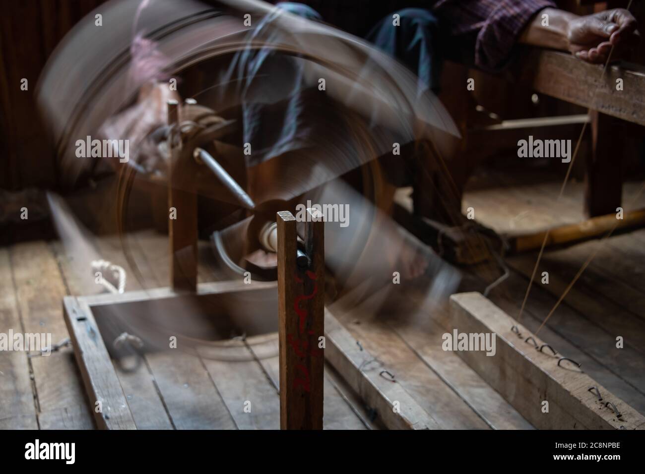Silk being spun into thread on traditional wooden spinning wheel. Fast