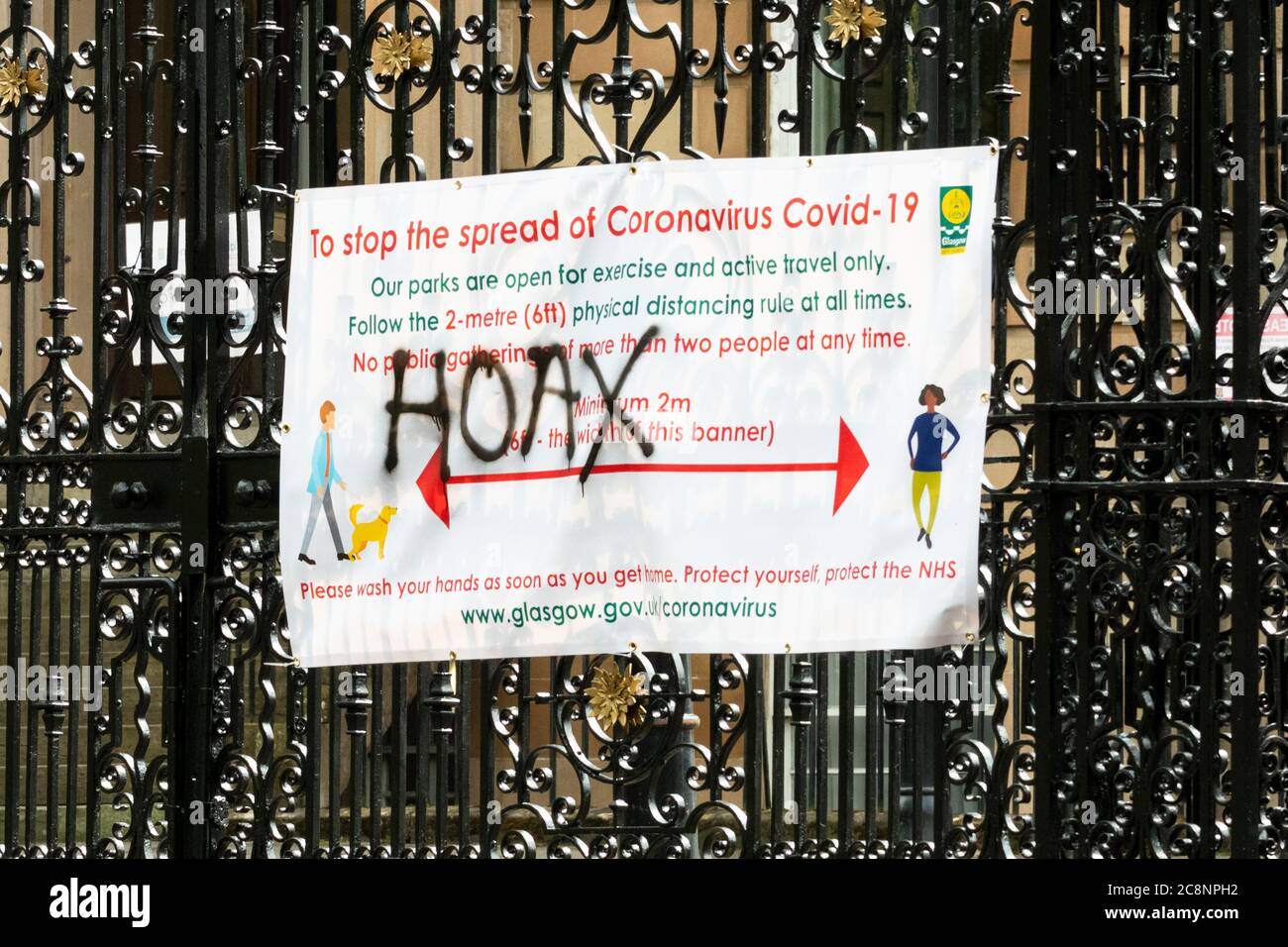 Hoax graffitied on Coronavirus Covid-19 information hoarding sign in Kelvingrove Park, during coronavirus lockdown, Glasgow, Scotland, UK Stock Photo