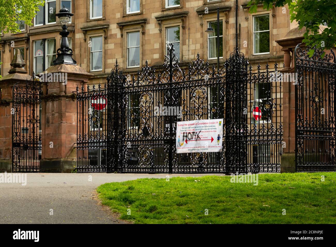 Hoax graffitied on Coronavirus Covid-19 information hoarding sign in Kelvingrove Park, during coronavirus lockdown, Glasgow, Scotland, UK Stock Photo