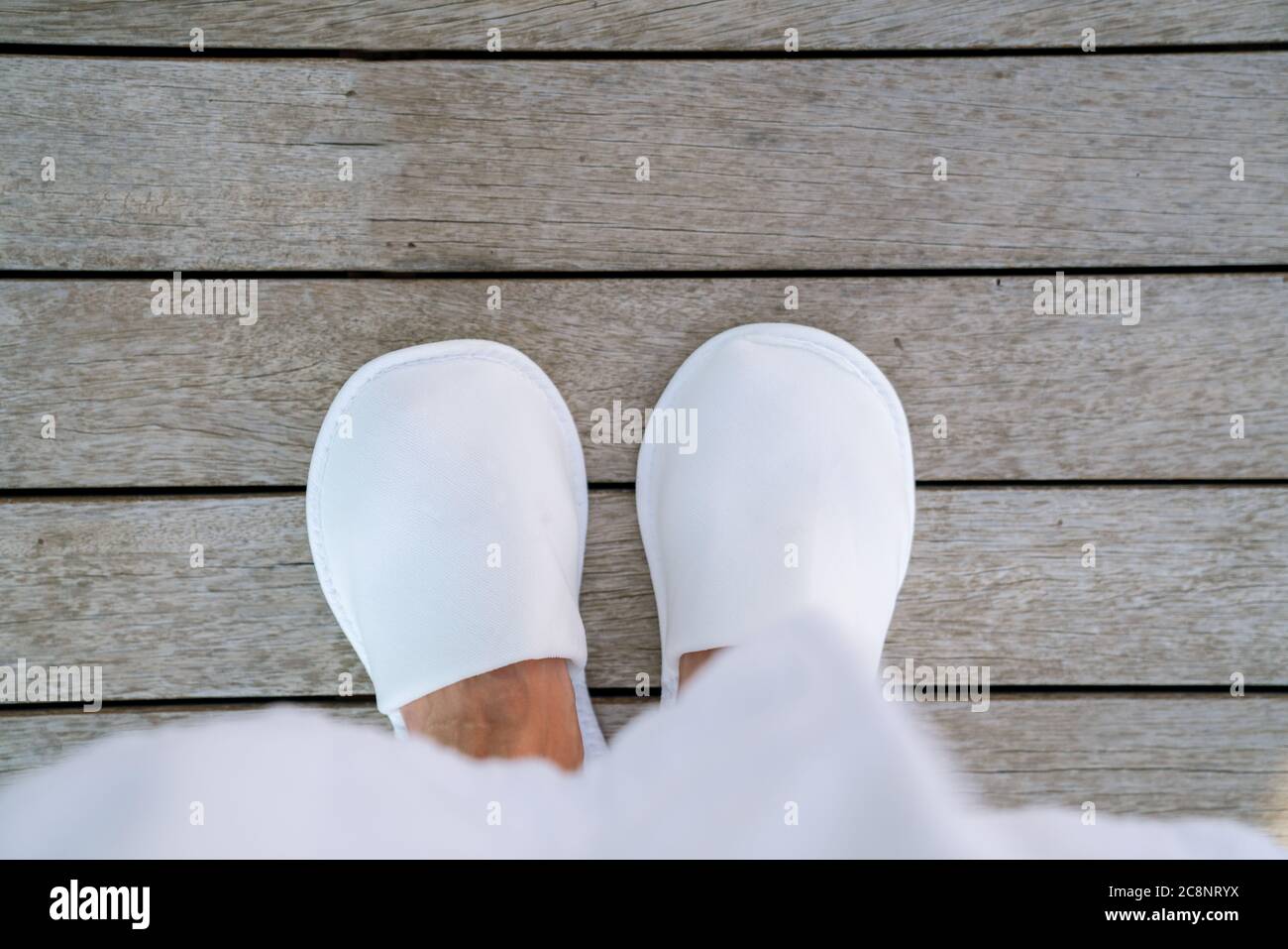 Woman staying in white slippers on wooden floor in hotel terrace. Top View . High quality photo Stock Photo