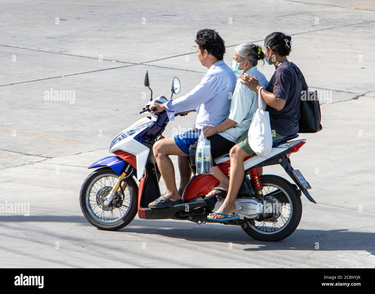 SAMUT PRAKAN, THAILAND, JUL 01 2020, A group of people riding a motorcycle on a street. Stock Photo