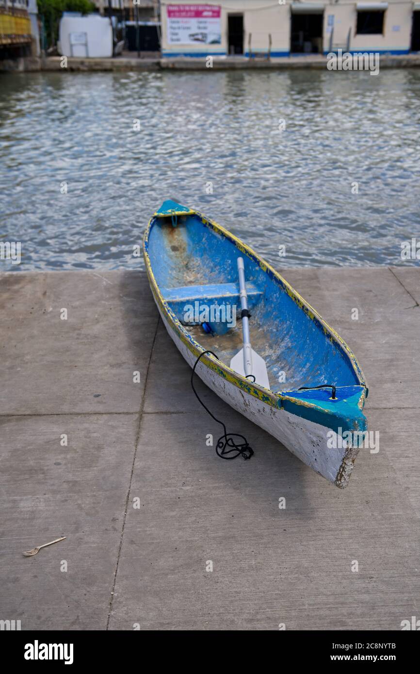 Rowboat with paddle docked in Belize City Belize near The Swing Bridge with random fork on ground Stock Photo