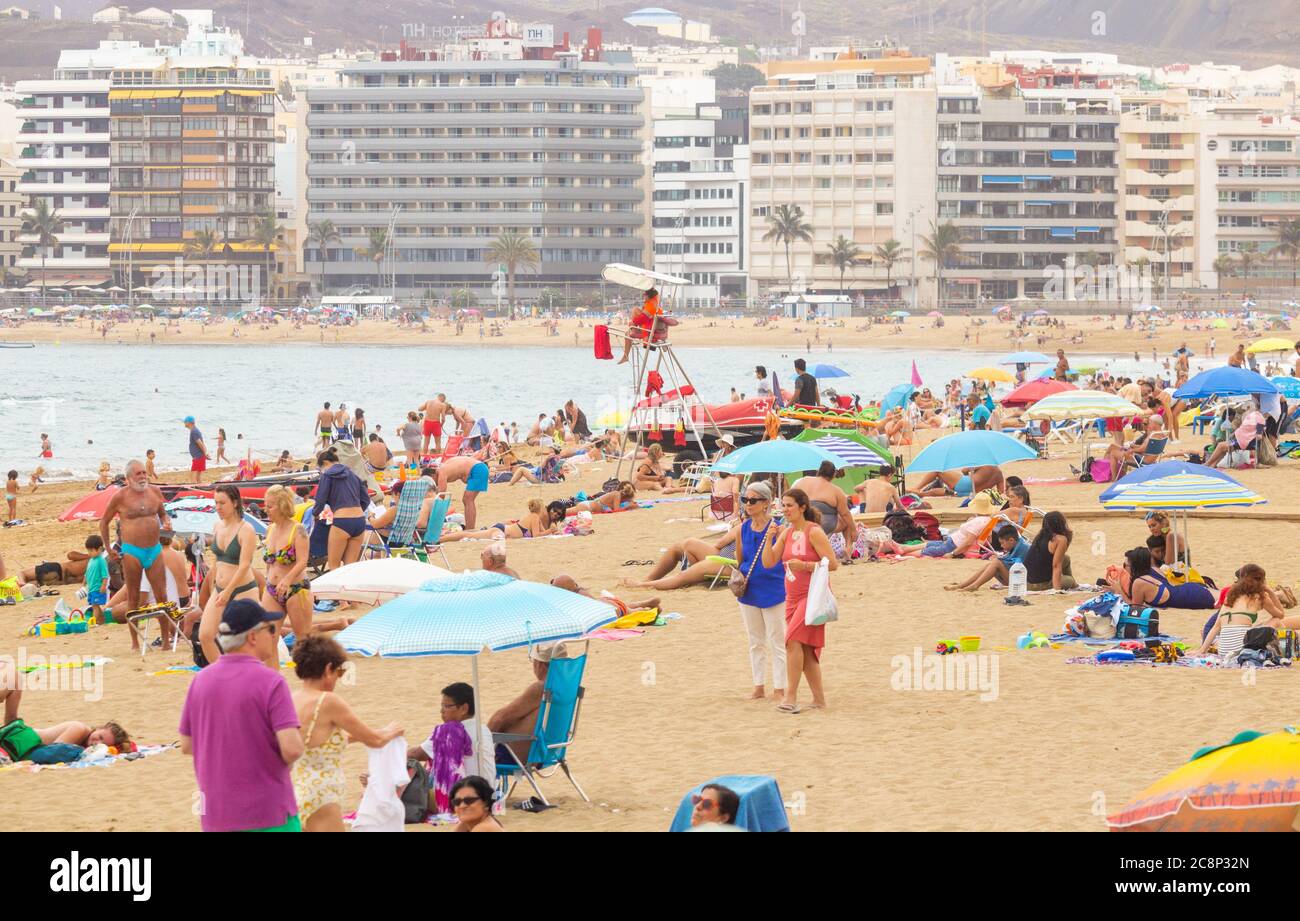 Las Palmas, Gran Canaria, Canary Islands, Spain. 26th July, 2020.  Tourists and locals on the city beach in Las Palmas on Gran Canaria as the government announces that  British tourists returning to the UK from Spain will have to quarentine for 14 days. Locals are keen to see the return of tourists as around 40% of the Canary Islands population depend on tourism for employment. Credit: Alan Dawson/Alamy Live News. Stock Photo