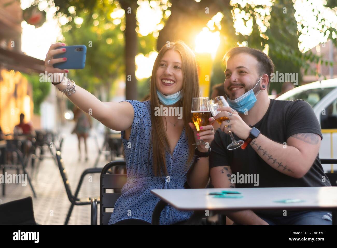 Spain Madrid. Caucasian couple toasting with beer wearing sanitary mask taking a selfie. Reopen pubs and club after quarentine coronavirus Covid-19. M Stock Photo