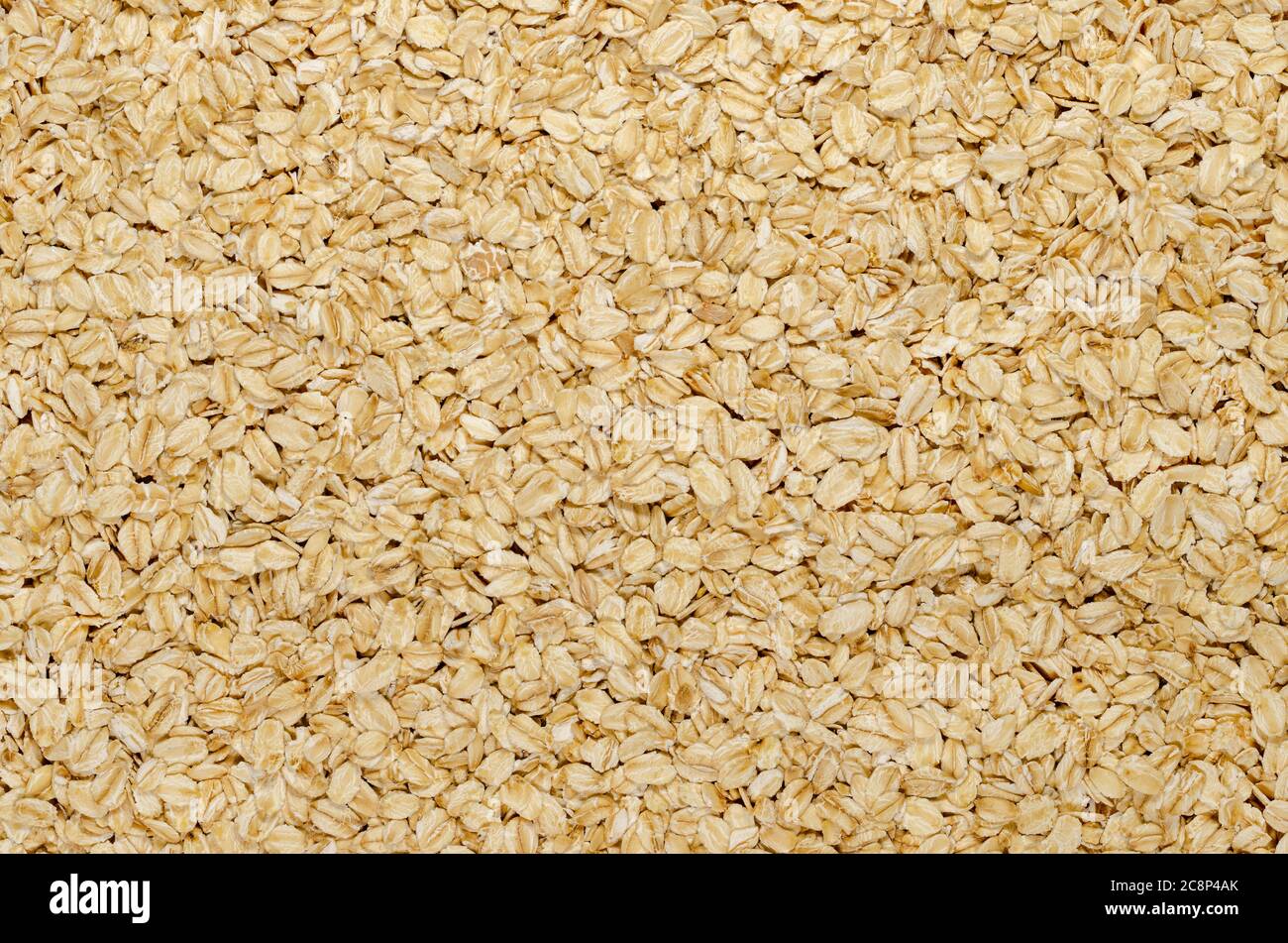 Rolled oats, surface and background. Lightly processed whole-grain food. Husked and steamed oat groats are rolled into flakes and lightly toasted. Stock Photo
