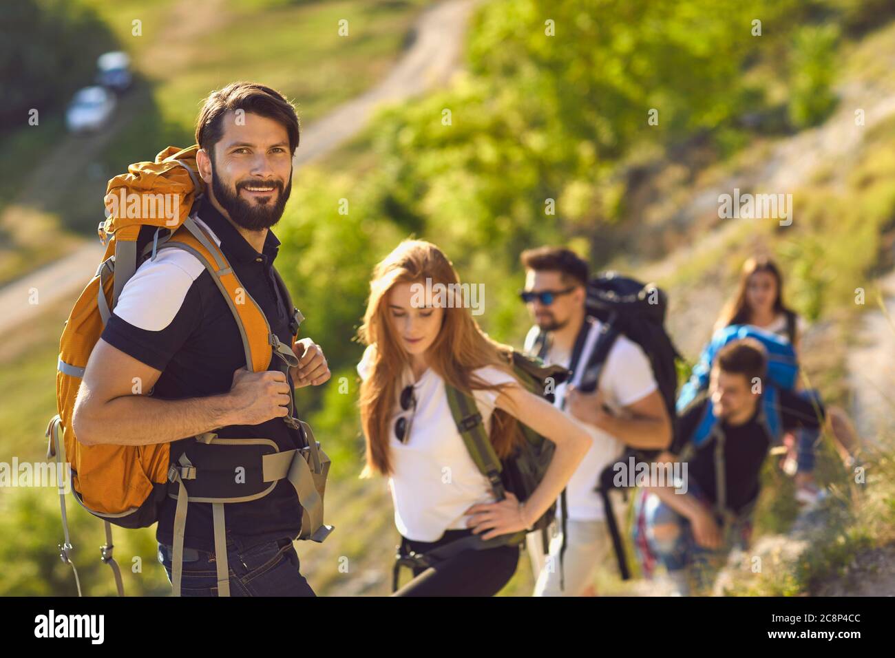 Male backpacker with his friends climbing to mountain top. Team of hikers mountaineering on summer vacation outside Stock Photo
