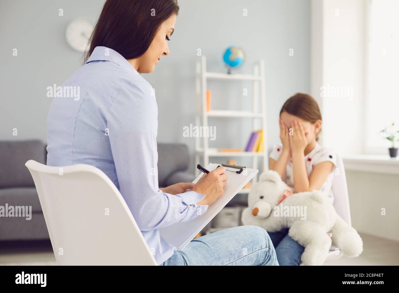 Young Psychologist is talking with a child in the room. Stock Photo