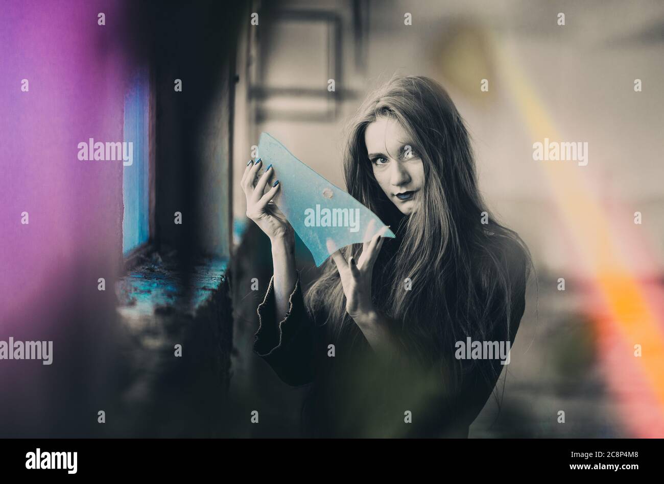 Girl dressed as witch holding broken glass, mirror, sign of bad luck. Halloween concept Stock Photo