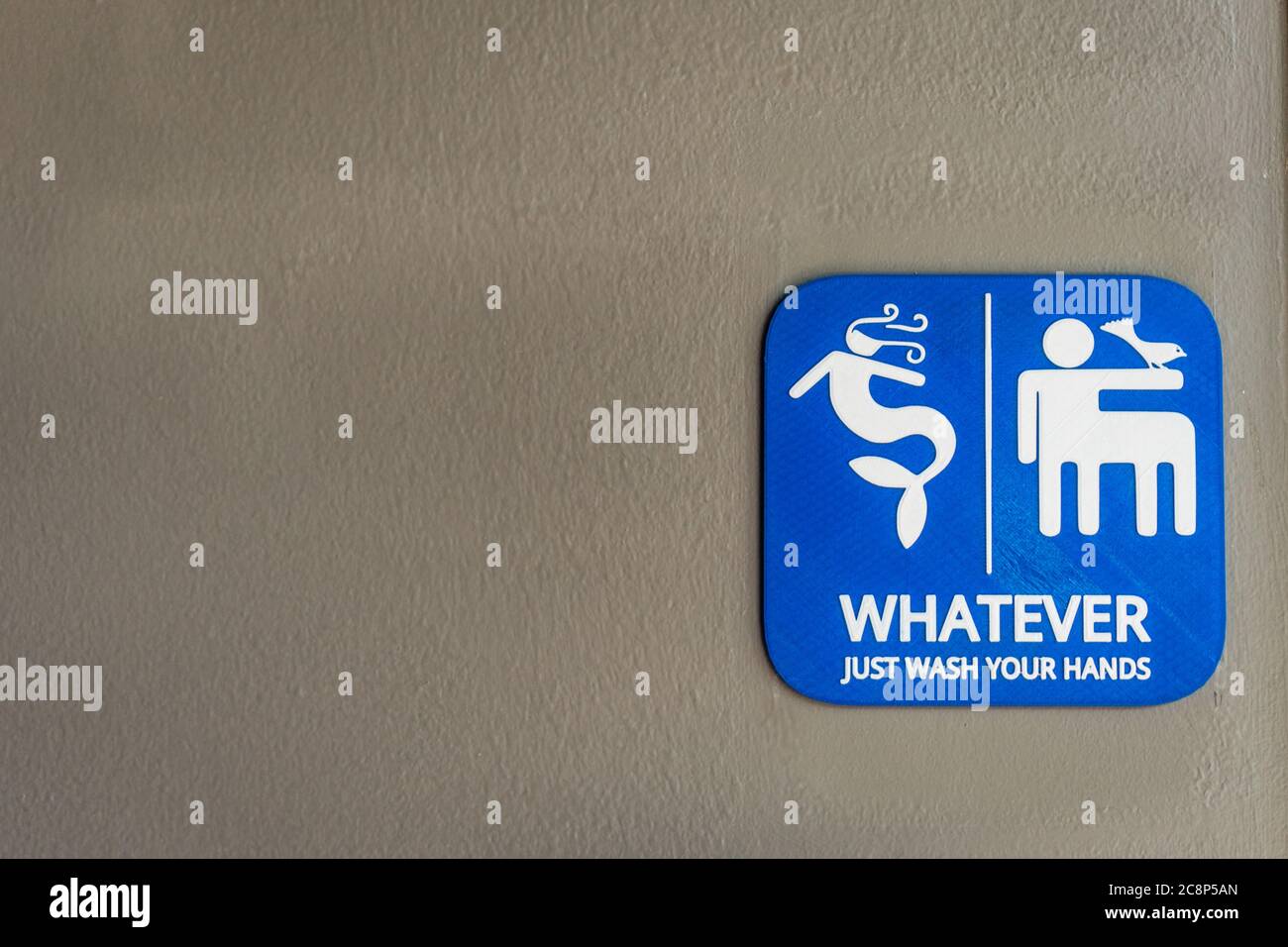 Close-up of bright blue unisex bathroom sign against neutral colored wall. Stock Photo