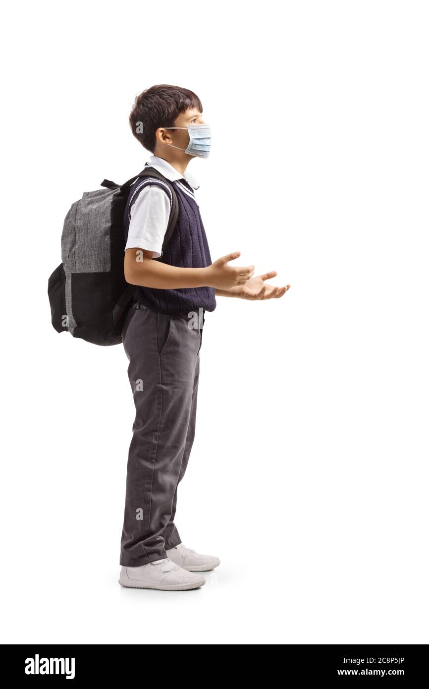 Full length profile shot of a schoolboy talking and wearing a protective face mask isolated on white background Stock Photo