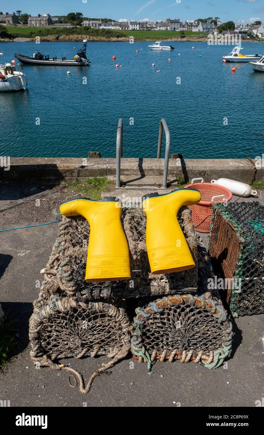 Yellow wellington boots laid out to dry on lobster creels in the harbour, Isle of Whithorn, Dumfries & Galloway, Scotland. Stock Photo